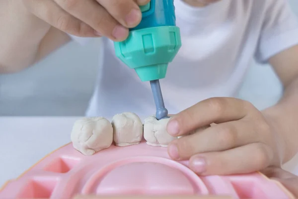 El niño tiene 5 años y juega en la colección de Dr. y taladros de relleno de boro dental en los dientes de arcilla Fotos de stock