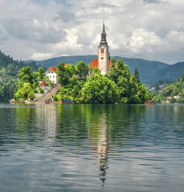 Bled, Slovenya - 20 Mayıs 2018: Güzel göl Julian Alps ve varsayım Mary Kilisesi'nin Bled, Slovenya kanadı. Dağlar, göl ve dramatik gökyüzü ortasında eski kilise.