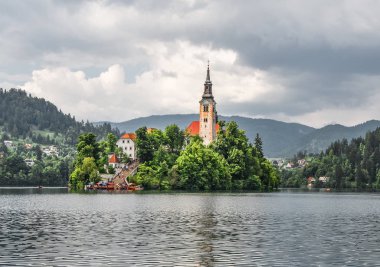 Bled, Slovenya - 20 Mayıs 2018: Güzel göl Julian Alps ve varsayım Mary Kilisesi'nin Bled, Slovenya kanadı. Dağlar, göl ve dramatik gökyüzü ortasında eski kilise.