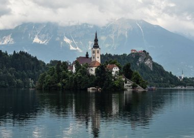 Bled, Slovenya - 20 Mayıs 2018: Güzel göl Julian Alps ve varsayım Mary Kilisesi'nin Bled, Slovenya kanadı. Dağlar, göl ve dramatik gökyüzü ortasında eski kilise.