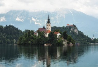 Bled, Slovenya - 20 Mayıs 2018: Güzel göl Julian Alps ve varsayım Mary Kilisesi'nin Bled, Slovenya kanadı. Dağlar, göl ve dramatik gökyüzü ortasında eski kilise.
