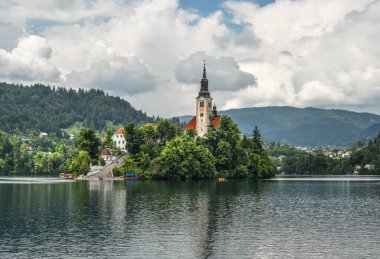 Bled, Slovenya - 20 Mayıs 2018: Güzel göl Julian Alps ve varsayım Mary Kilisesi'nin Bled, Slovenya kanadı. Dağlar, göl ve dramatik gökyüzü ortasında eski kilise.