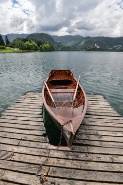 Güzel Lake Bled Julian Alps ve eski ahşap tekne. Dağlar, turistik gemi, göl ve dramatik gökyüzü.