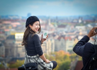 Güzel Asyalı kız poz veriyor, starbucks kahve tutar ve Prag eski şehir görünüyor