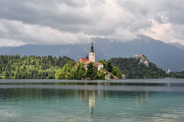 Julian Alpleri 'nde Bled güzel Gölü ve Mary Kilisesi, Bled Slovenya varsayımı. Dağlar, gölün ortasında eski kilise ve dramatik gökyüzü.
