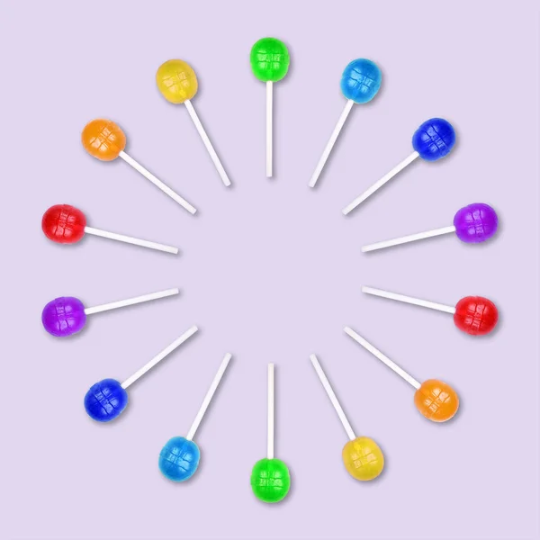 Conjunto de piruletas coloridas agrupadas en un círculo aislado sobre fondo púrpura claro . —  Fotos de Stock