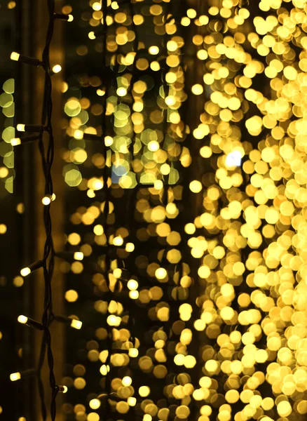 Decoração de Natal feita de guirlanda brilhante. Iluminação de Ano Novo. Brilhante amarelo e dourado brilho luzes de fundo. Desfocado . — Fotografia de Stock