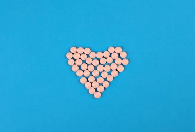 Tıbbi geçmişi var. Mavi arka planda kalp şeklinde pembe haplar. Düz yatıyordu.