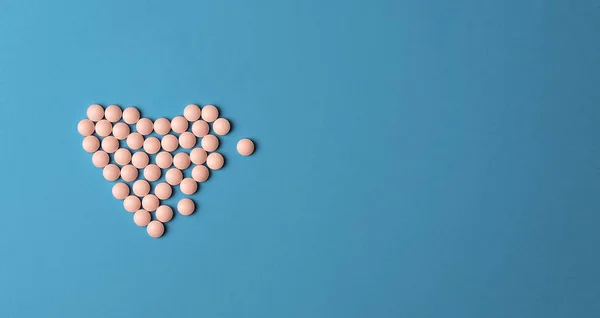 Medical background. Pink Pills in form of heart on blue background. Flat lay. — 스톡 사진