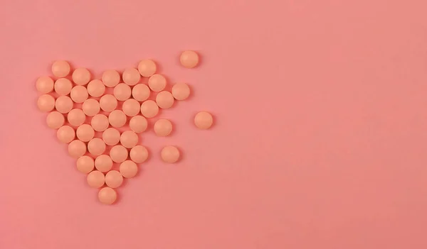 Concept de la Journée mondiale du cœur. Une formation médicale. Pilules roses en forme de coeur sur fond rose . — Photo