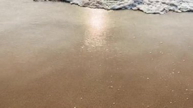 Beyaz köpüklü okyanus dalgaları altın kumlu sahile yavaşça vuruyor. Huzurlu bir sahil sahnesi yaratıyor. Rahatlamayı, yazı, tatili ve doğal deniz güzelliğini simgeliyor.