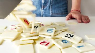 Bir kadın domino benzeri fayansları beyaz bir masada oynanan bir masa numaralarıyla ayırıyor, boş zamanlarında oyun, strateji ve eğlenceye hazırlanıyor.