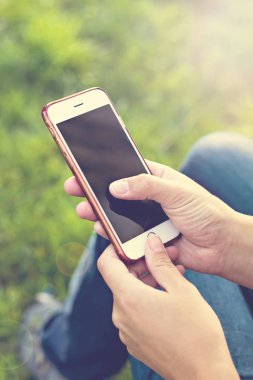 Bir şezlong arka planı yeşil çim kadının elinde cep telefonu. Dinlenme zamanı. İş dinlenme tatile bir akıllı telefon kullanan kadın, yalan ayakları kızlar, açık havada, park, yaz