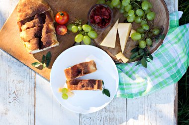 Peynir ve kurutulmuş domates ile meyveli turta. Akşam yemeği için sofrayı. Öğle Yemeği. Ev yapımı pasta, turta ve aperatifler, sebze, meyve, peynir.