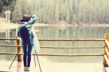 Bir kız fotoğrafçı bir tripod fotoğraf yağmurda alır..