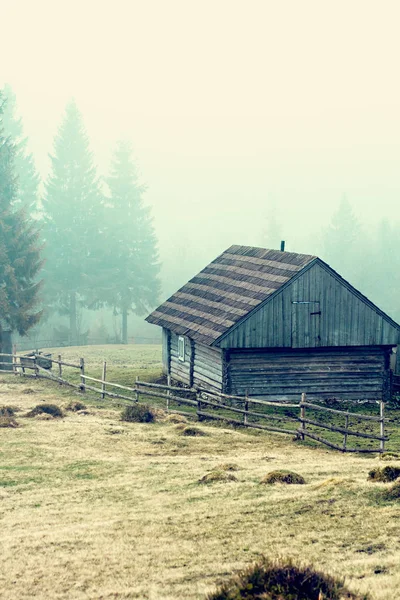 Mountain landscape in the fog. house in the mountains. Carpathian mountains. The old spooky house on the land of nowhere. Wooden house in the middle of the barren land. Scenic retro landscape.