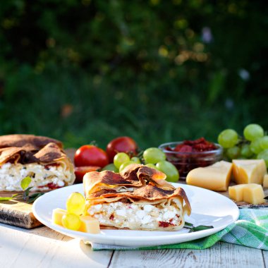 Peynir ve kurutulmuş domates ile meyveli turta. Akşam yemeği için sofrayı. Öğle Yemeği. Ev yapımı pasta, turta ve aperatifler, sebze, meyve, peynir.