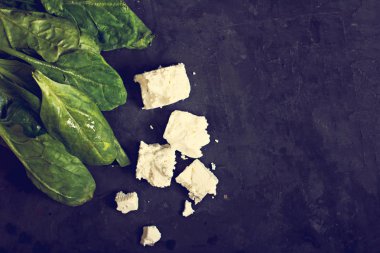 Ispanak ve peynir karanlık bir arka plan üzerinde.