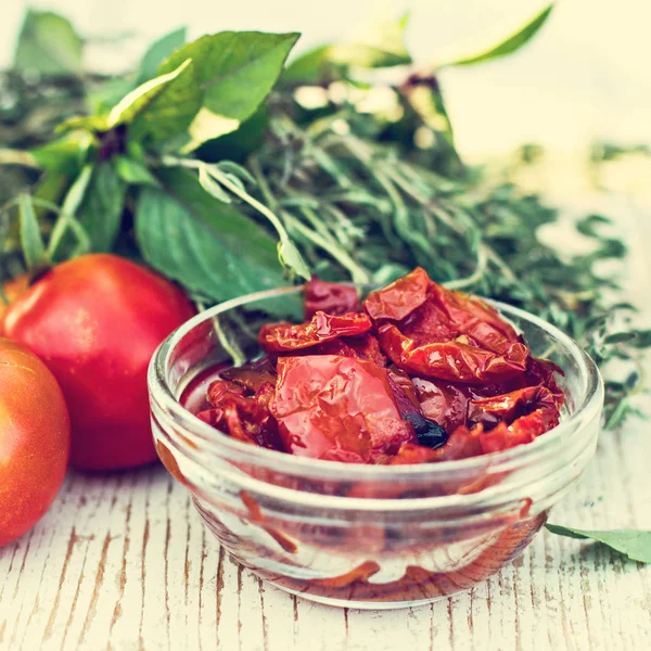 Sun dried tomatoes and aromatic herbs - thyme, basil, rosemary. Sun dried tomatoes with herbs and sea salt in olive oil in a glass jar