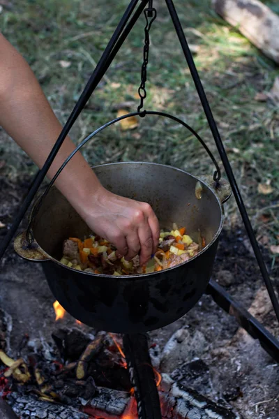 A pot of meat over a fire. Hike, summer vacation, outdoor recreation, outdoor food. Cooking over a campfire. tourist kettle over campfire.