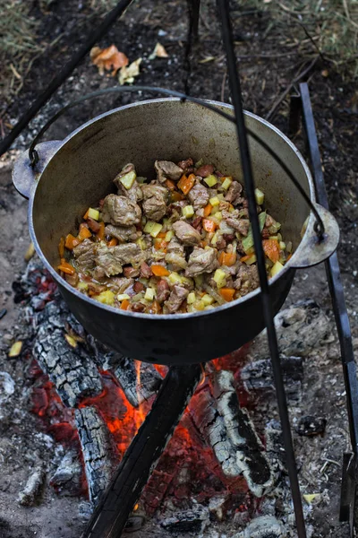 A pot of meat over a fire. Hike, summer vacation, outdoor recreation, outdoor food. Cooking over a campfire. tourist kettle over campfire.