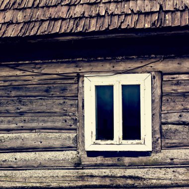 Eski bir ahşap ev. Bir pencerede bir ahşap ev. Eski bir ahşap evin duvarına küçük bir pencerede