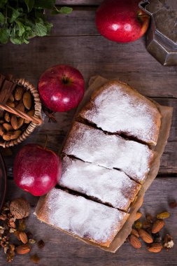 Ev yapımı elma strudel taze elma, tarçın ve pudra şekeri ile eski ahşap arka plan üzerinde hizmet dilimlenmiş. Yakın, karanlık rustik tarzı Apple strudel.