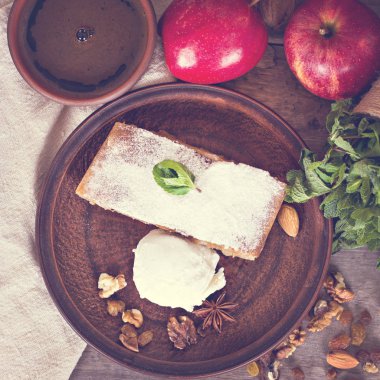 Ev yapımı elma strudel taze elma, tarçın ve pudra şekeri ile eski ahşap arka plan üzerinde hizmet dilimlenmiş. Yakın, karanlık rustik tarzı Apple strudel.