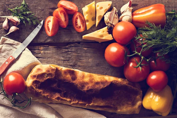 Ev yapımı tavuk, peynir ve eski bir ahşap masa üzerinde beyaz soslu sebze meyveli turta. Rustik tarzı.