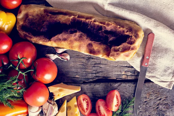 Ev yapımı tavuk, peynir ve eski bir ahşap masa üzerinde beyaz soslu sebze meyveli turta. Rustik tarzı.