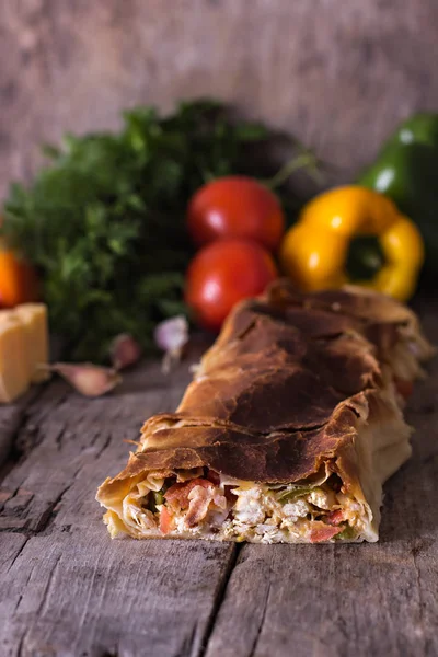 Ev yapımı tavuk, peynir ve eski bir ahşap masa üzerinde beyaz soslu sebze meyveli turta. Rustik tarzı.