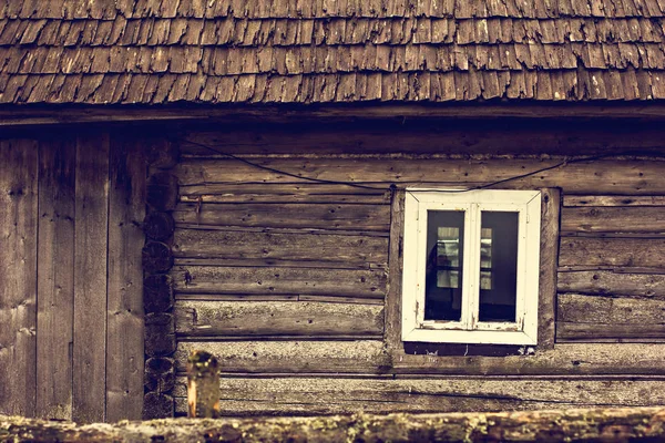 An old wooden house. A window in a wooden house. A small window in the wall of an old wooden house
