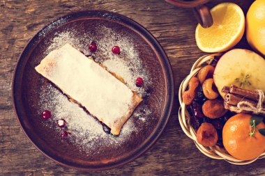meyveli turta ve kış dekor. Apple strudel (pasta) kurutulmuş meyve, portakal, kızılcık, ceviz ve pudra şekeri ile. Rustik tarzı.