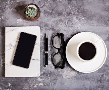 Not defteri, günlük, Gözlük, cep telefonu, kahve, çimento zemin üzerine sulu ile Resepsiyon çalışma alanı. İş natürmort. İş kavramı. düz yatıyordu, en iyi görünümü