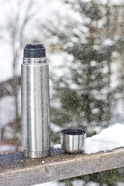 Thermos on the background of the winter landscape.