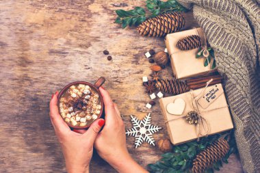  Bir kadın eli bir Kupası tutar. Hediye, koniler, hediyeler, kahve, kakao. Noel, yeni yıl arka plan. Kış, yeni yıl, yılbaşı natürmort. 