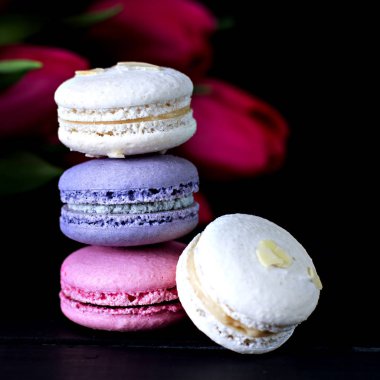 Macarons tanımlama karanlık bir arka plan üzerinde. Boş alan, seçici odak içeren koyu arka plan üzerinde renkli acıbadem kurabiyesi kurabiye ve tatlı kule