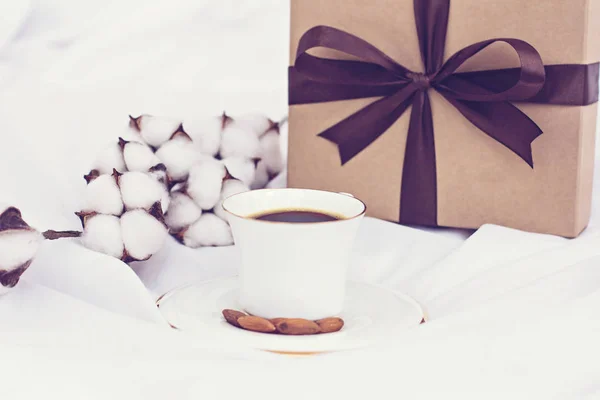cotton branch, gift and coffee.  Gift, coffee, cotton branch. Near an envelope with a heart to send and a box with a gift and a cotton branch. Concept for Valentine\'s Day or Women\'s Day or Mother\'s Day.