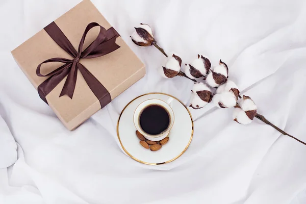 cotton branch, gift and coffee.  Gift, coffee, cotton branch. Near an envelope with a heart to send and a box with a gift and a cotton branch. Concept for Valentine\'s Day or Women\'s Day or Mother\'s Day.