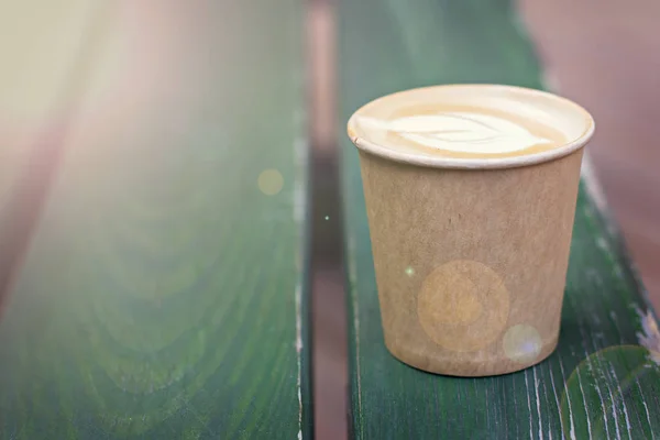 Café capuchino en taza de papel sobre la mesa vieja de madera —  Fotos de Stock