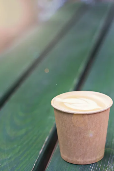 Café capuchino en taza de papel sobre la mesa vieja de madera —  Fotos de Stock