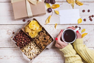 Eski ahşap arka planda bir kutu fındık ve kurutulmuş meyve. Fındık, kaju, kurutulmuş baba, kurutulmuş ananas. Yıldönümünde bir hediye. Hediye olarak fındık.