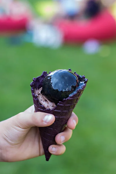 Chifre com sorvete preto na mão . — Fotografia de Stock