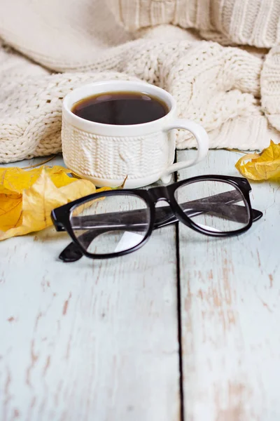 Blanco cálido de punto a cuadros, café, teléfono, gafas, hojas de otoño sobre un fondo de madera . —  Fotos de Stock