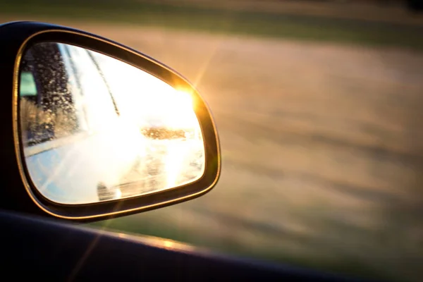 side mirror in a car in which the sunset is reflected.