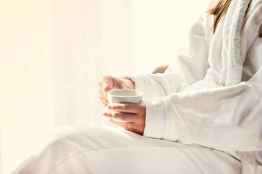 Beyaz önlüklü bir kız sabah kahvesini içiyor..