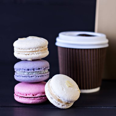 Macarons tanımlama karanlık bir arka plan üzerinde. Boş alan, seçici odak içeren koyu arka plan üzerinde renkli acıbadem kurabiyesi kurabiye ve tatlı kule