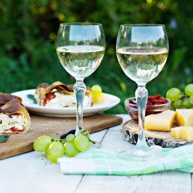 Beyaz şarap ve hafif atıştırmalıklar, üzümler, şarap, peynir, turta. Doğada romantik yaz yemeği..