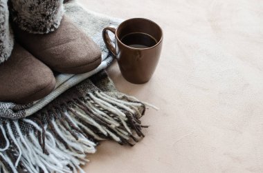 Sıcak ev kıyafetleri. Yünlü ekose kumaş, terlik ve bir fincan sıcak içecek..