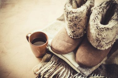 Sıcak ev kıyafetleri. Yünlü ekose kumaş, terlik ve bir fincan sıcak içecek..